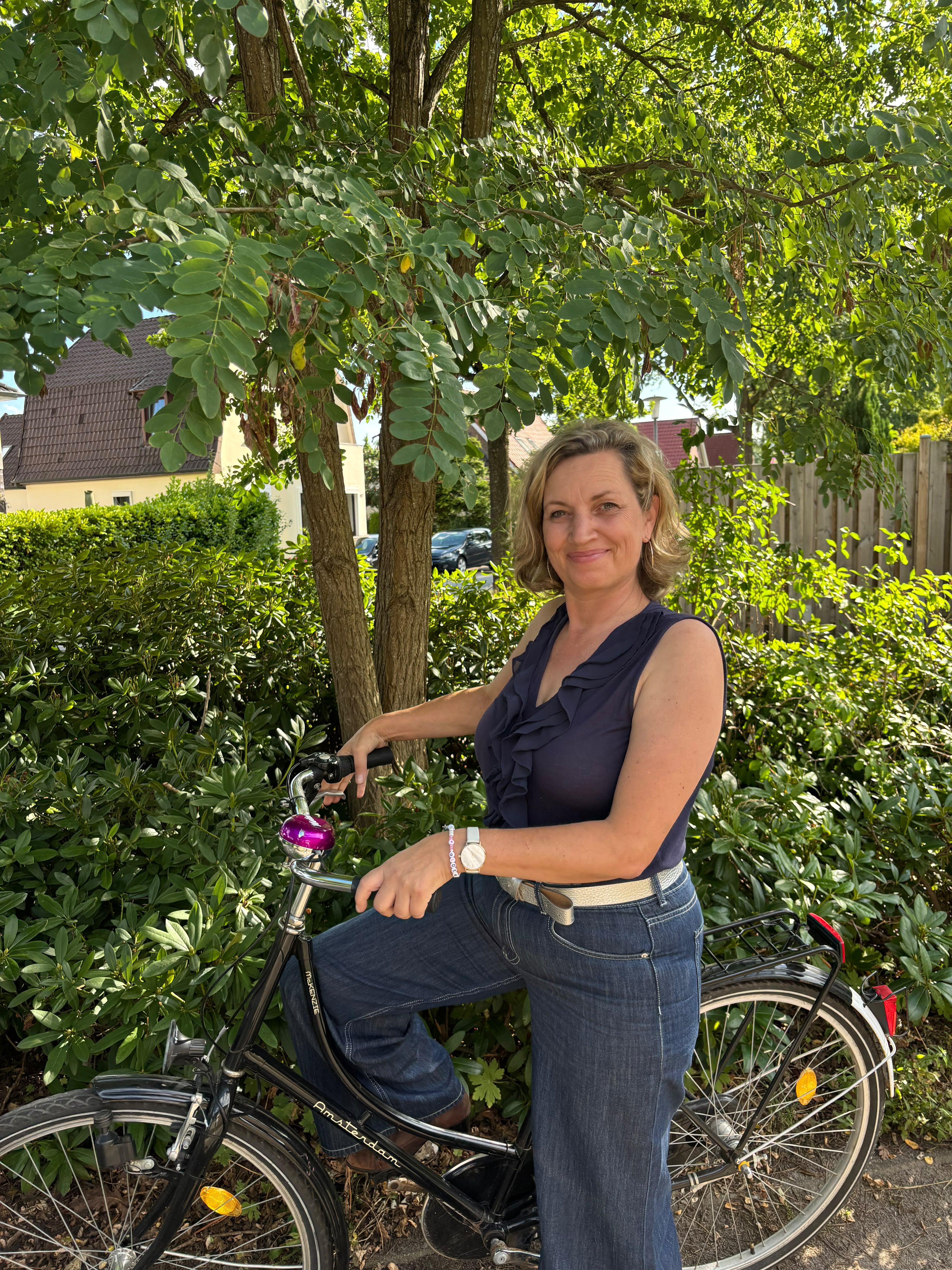 Byanca Küßner mit dem Fahrrad in einer begrünten Oldenburger Wohnstraße